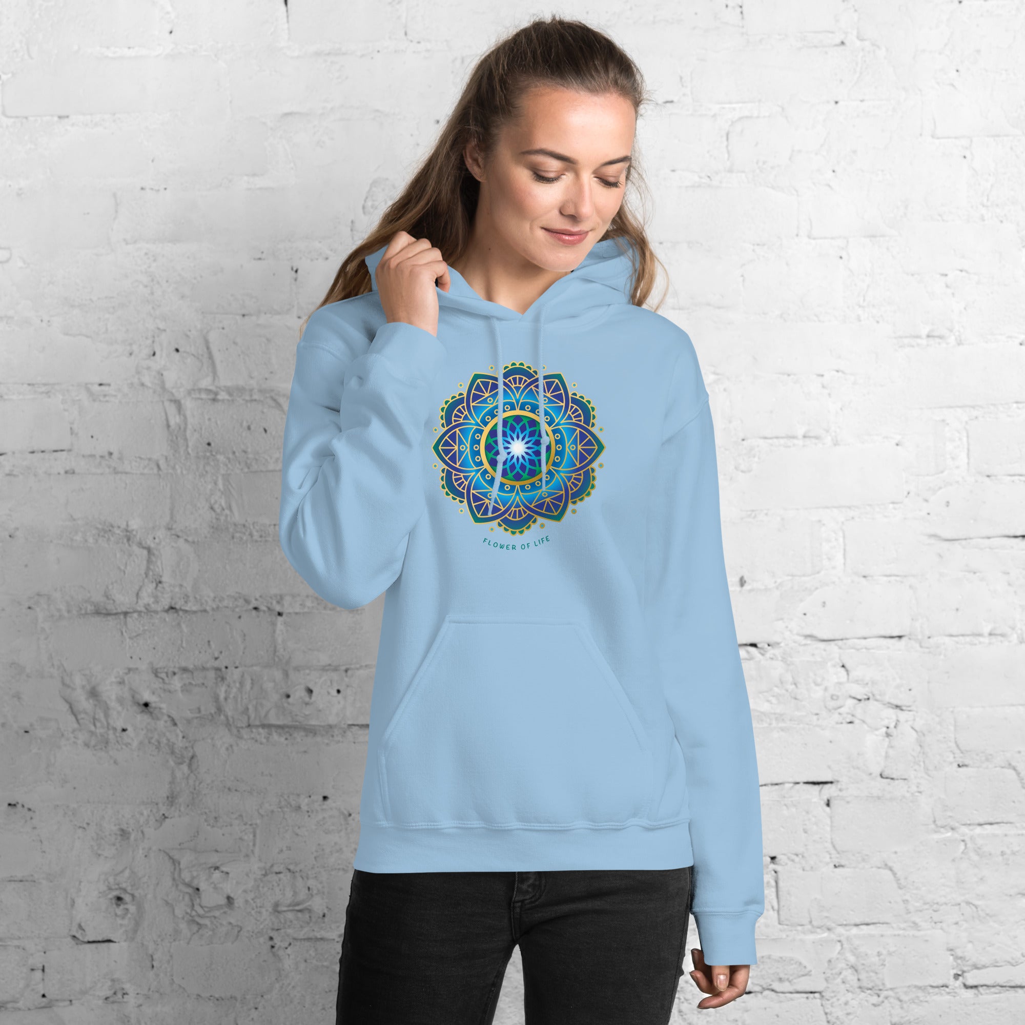 Woman wearing a light blue hoodie with a colorful flower of life mandala design .