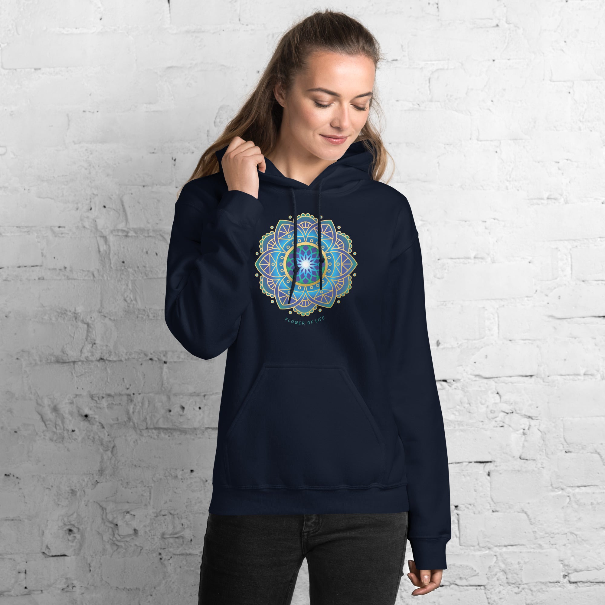 Woman wearing a navy blue hoodie with a colorful flower of life mandala design .